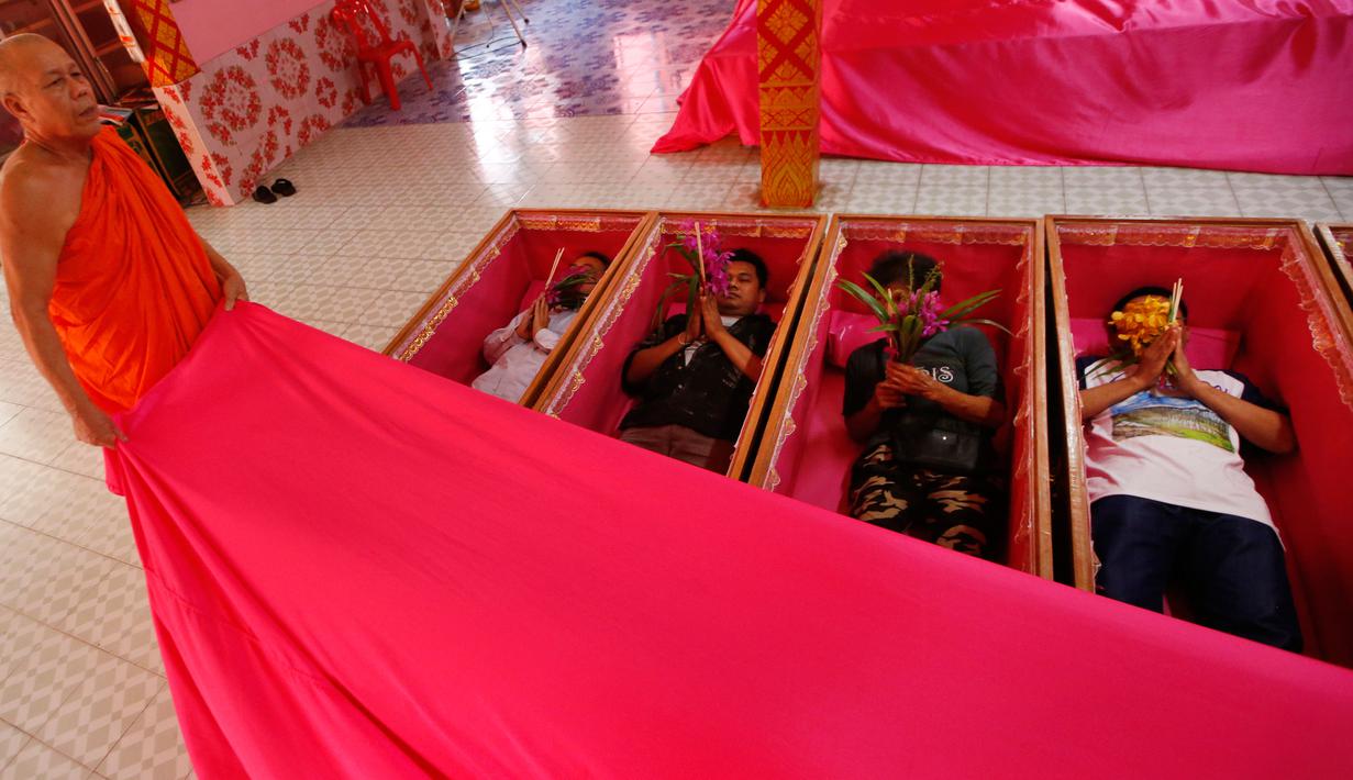 Seorang biksu menutup para pemuja dengan kain ketika berbaring dalam peti mati di kuil Takien, pinggiran Bangkok, Thailand, Senin (31/12). Upacara agama ini bagian dari ritual untuk menerima kematian yang tidak bisa dihindari manusia (AP/Sakchai lalit)