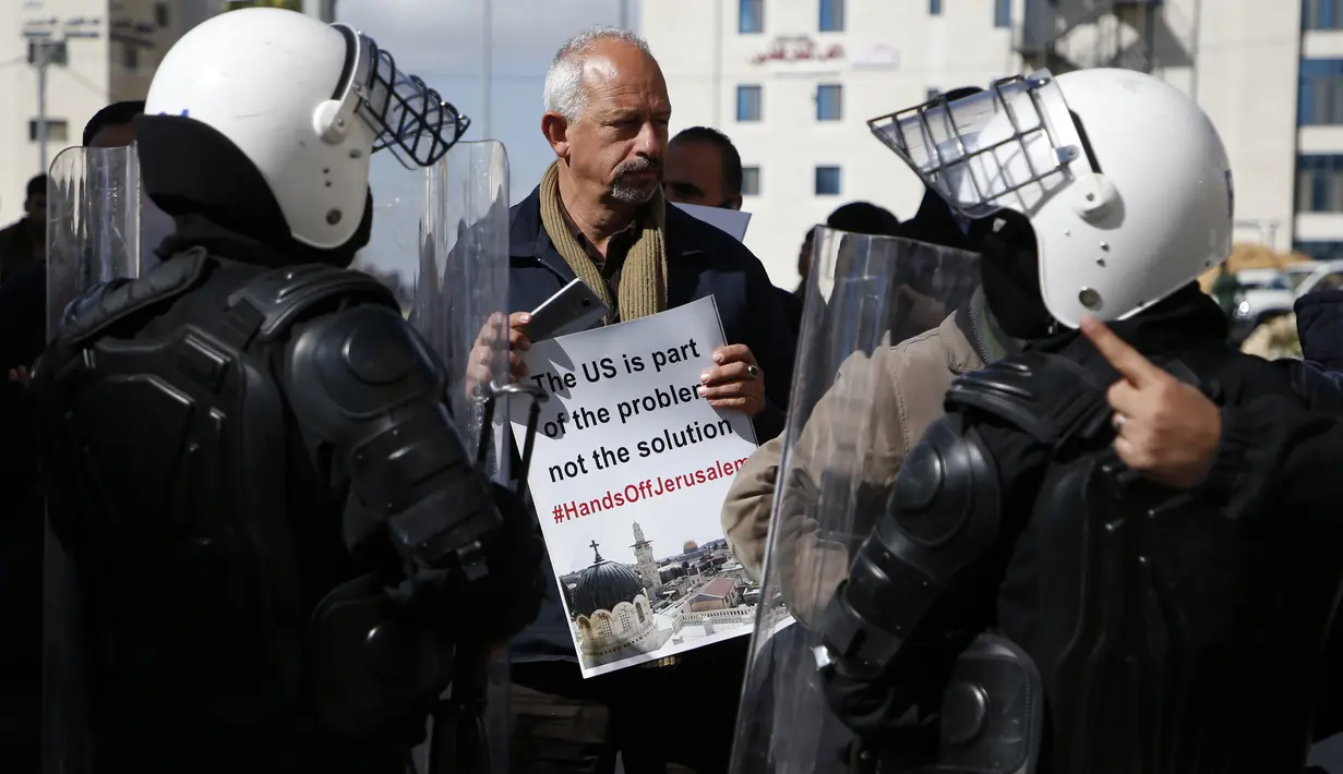 Polisi Palestina menghalau demonstran yang mendekati delegasi AS di Ramallah, Tepi Barat, Kamis (22/2). Delegasi AS dilempari telur sebagai protes atas deklarasi Donald Trump yang mengakui Yerusalem sebagai ibu kota Israel. (ABBAS MOMANI/AFP)