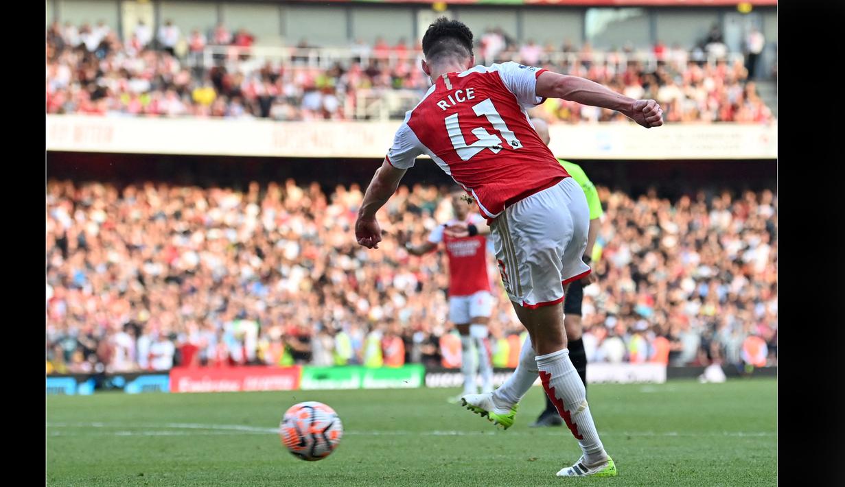 Pemain Arsenal, Declan Rice, menendang bola ke gawang MU dan membuahkan gol setelah memanfaatkan sepak pojok di babak tambahan waktu dan menjadi pahlawan kemenangan Arsenal dalam pertandingan pekan keempat Liga Inggris 2023/2024 yang berlangsung di Emirates Stadium, London, Senin (4/9/2023) dini hari WIB. (AFP/Glyn Kirk)