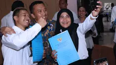 Sejumlah atlet berswafoto dengan Menpora Imam Nahrawi usai menerima SK CPNS di Wisma Kemenpora, Jakarta, Selasa (2/4). 286 atlet berprestasi menerima SK pengangkatan sebagai CPNS di lingkungan Kemenpora. (Liputan6.com/Helmi Fithriansyah)