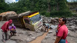 Peristiwa yang terjadi pada Selasa (3/3/2026) sore sekitar pukul 15.30 WIB menewaskan tiga orang. Tampak dalam foto, warga berusaha mengambil bagian-bagian truk yang terkubur di pasir setelah longsor lumpur akibat hujan dari Gunung Merapi di Sungai Senowo, Magelang, Jawa Tengah pada Rabu 4 Maret 2026. (Devi Rahman/AFP)