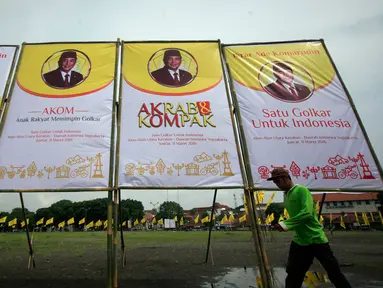 Seorang pekerja melintasi baliho Ade Komarudin di kawasan alun alun utara Yogyakarta, Jumat (11/3/2016). Ade Komarudin akan mendekalrasikan pencalonan ketua Umum DPP Golkar yang akan bertarung pada Munaslub 2016. (Liputan6.com/Boy Harjanto)