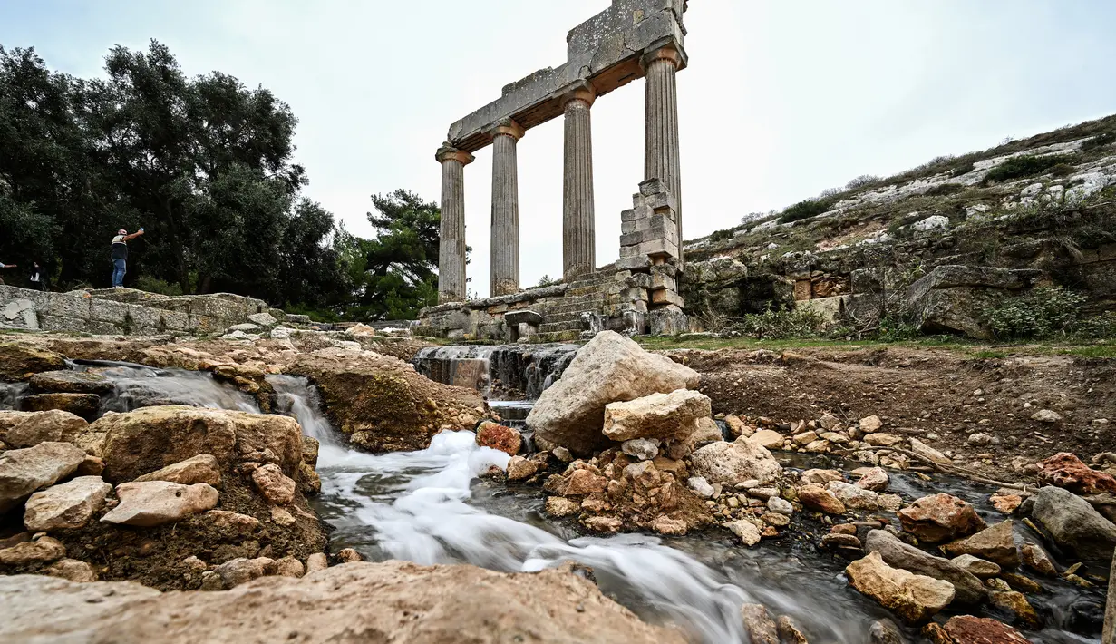 Air mengalir melalui reruntuhan di lokasi kota kuno Cyrene (Shahhat) Yunani-Romawi di Libya timur, sekitar 60(37 mil) barat Derna setelah banjir dahsyat, pada 21 September 2023. (Ozan KOSE / AFP)
