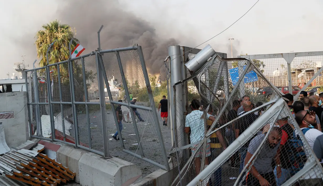 Orang-orang berkumpul di pintu masuk utama pelabuhan Beirut yang rusak, tempat terjadinya ledakan besar di Beirut, Lebanon pada Selasa (4/8/2020). Ledakan yang diduga dari gudang berisi 2.750 ton amonium nitrat meratakan hampir seluruh bangunan di sekitar Pelabuhan di kota Beirut. (AP Photo/Hussein