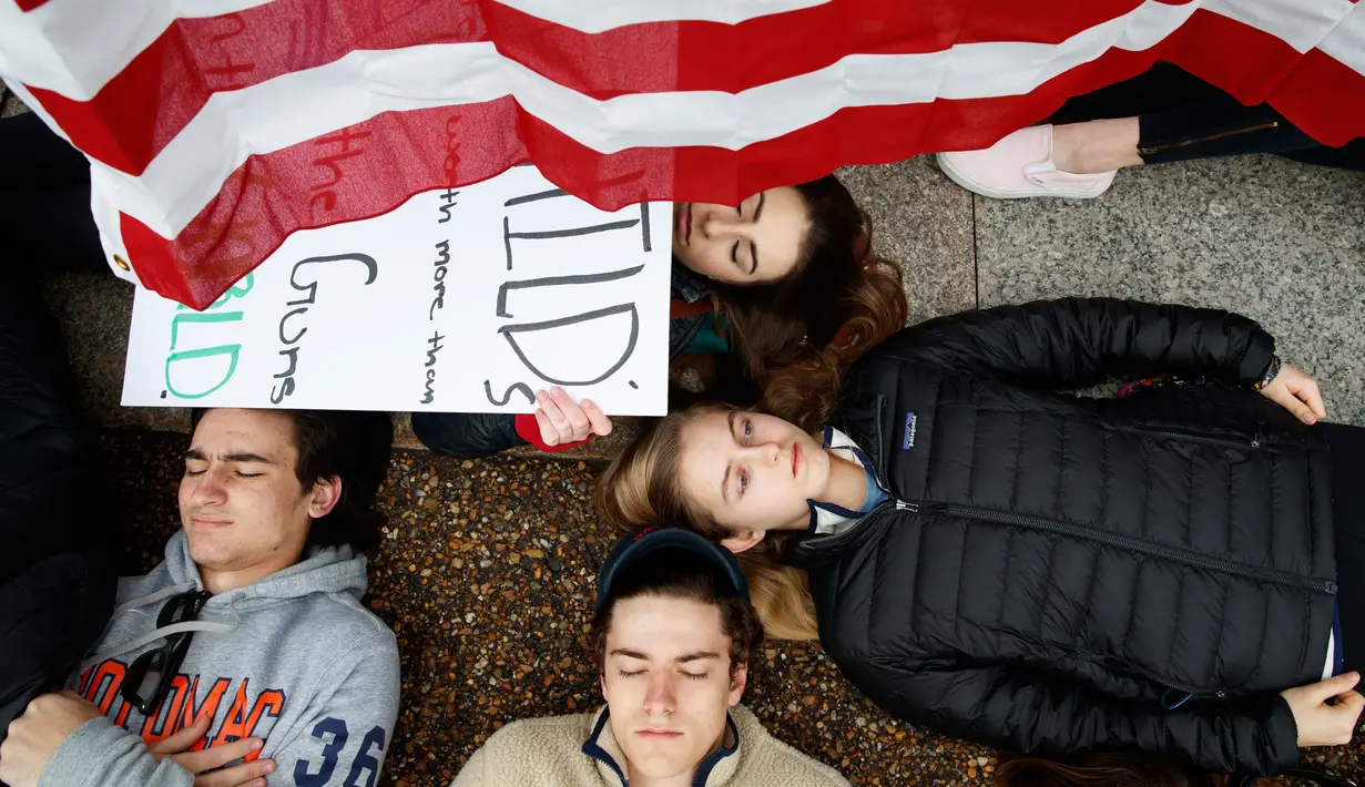 Anna Hurley (15) bersama pengunjuk rasa lainnya berbaring di jalan depan Gedung Putih, Washington, Senin (19/2). Aksi tersebut meminta Presiden Donald Trump menekan Parlemen akan membuat aturan yang memperketat kepemilikan senjata. (AP Photo/Evan Vucci)