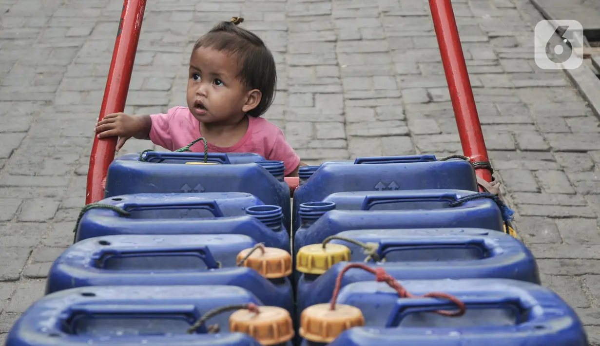 Seorang anak saat berada di gerobak air pikulan di kampung nelayan Kalibaru, Cilincing, Jakarta Utara, Selasa (22/3/2022). Sementara untuk kebutuhan MCK, warga tetap menggunakan air sumur yang diendapkan terlebih dahulu. (merdeka.com/Iqbal S Nugroho)