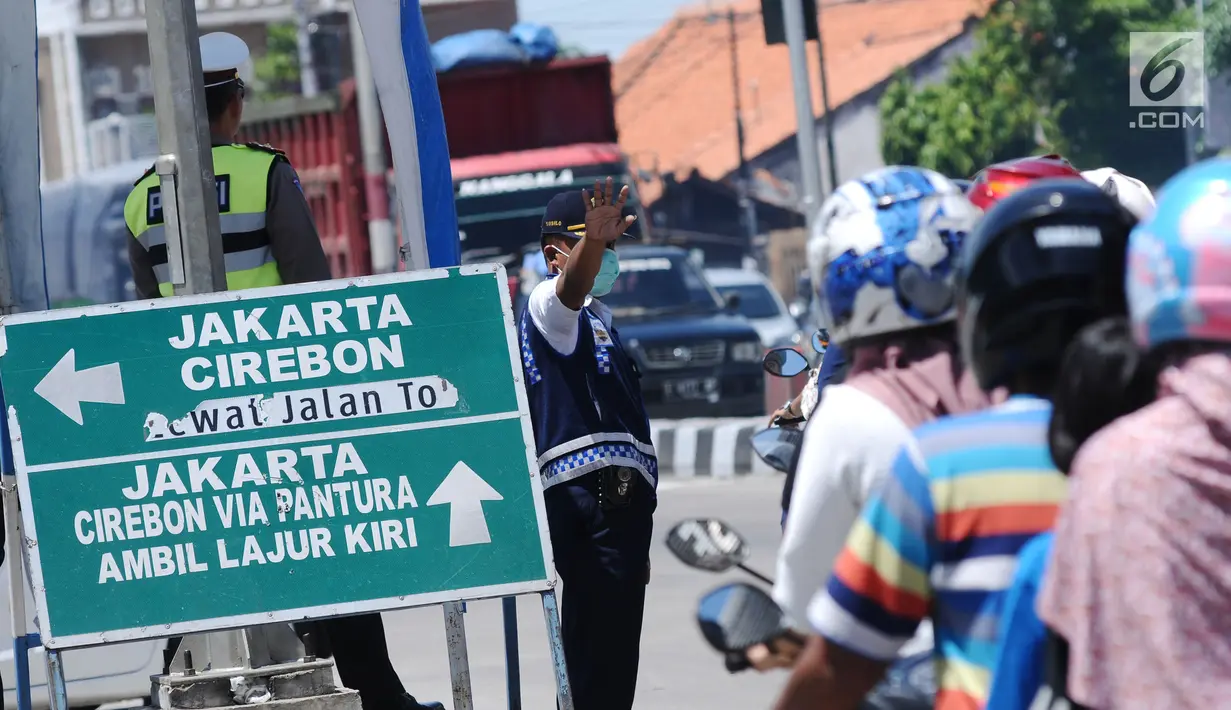 Petugas mengatur arus lalu lintas di Simpang Tiga Keluar Tol Brebes, Jawa Tengah, Sabtu (23/12). Memasuki libur panjang Natal 2017, arus lalu lintas di Simpang Tiga Keluar Tol Brebes terlihat ramai lancar. (Liputan6.com/Helmi Fithriansyah)