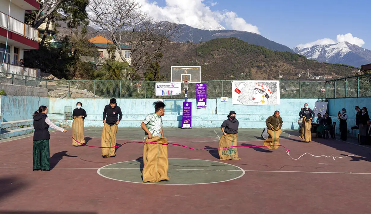 Orang-orang berlomba dalam perlombaan karung dalam sebuah pesta yang diselenggarakan oleh Asosiasi Wanita Tibet untuk memperingati Hari Perempuan Internasional di Dharmsala, India, 8 Maret 2022. (AP Photo/Ashwini Bhatia)