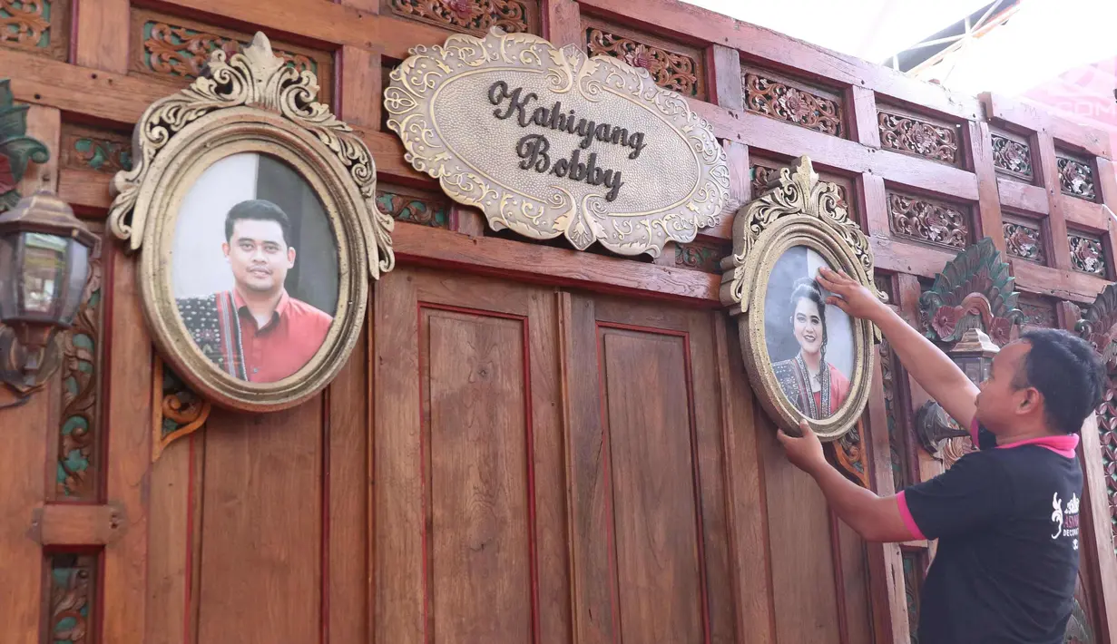Pekerja memasang pigura foto Putri Presiden Joko Widodo Kahiyang Ayu dan Bobby Nasution di Graha Saba, Solo, Senin (6/11). Pernikahan anak presiden tersebut akan berlangsung pada Rabu (8/11) esok. (Liputan6.com/Angga Yuniar)