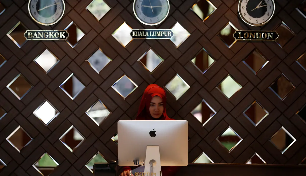 Seorang resepsionis mengamati layar komputer di balik meja di hotel Al Meroz, Bangkok, (29/8). Thailand yang mayoritas penduduknya Buddhis telah membuka hotel halal pertama dengan harapan akan menarik lebih banyak turis Muslim. (REUTERS/Chaiwat Subprasom)