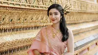 Ia mengenakan pakaian tradisional Thailand yang disebut dengan chut thai. Febby mengenakan chut thai atasan pink dipadukan bawahan mirip songket warna coklat. [Instagram/@febbyrastanty]