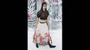 Kendall Jenner mengenakan crop top hitam yang tipis dipadu dengan rok panjang putih yang dihiasi bunga-bunga bernuansa putih, oranye dan biru saat acara Paris Fashion Week Haute Couture Spring/Summer 2015, Selasa (27/1). (AFP PHOTO/Patrick KOVARIK)