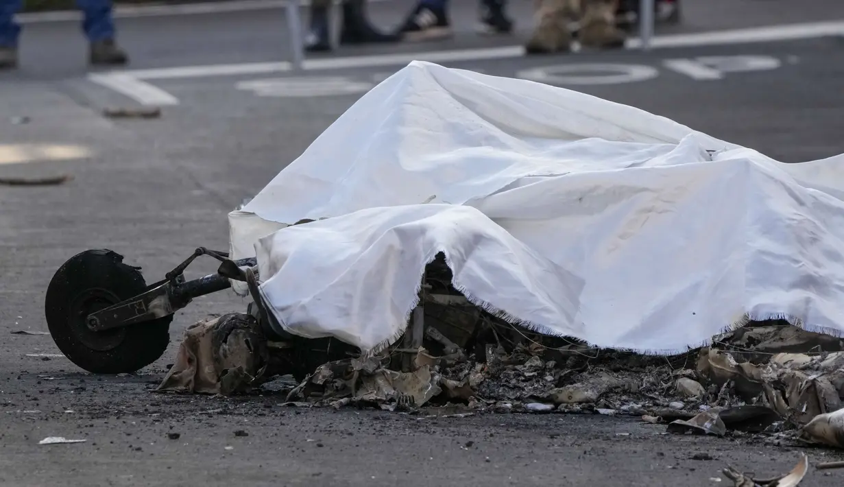 Sisa-sisa yang terbakar salah satu dari dua pesawat U-208 Angkatan Udara Italia yang jatuh ditutup dengan kain putih di distrik pemukiman tempat jatuhnya, di Guidonia, di pinggiran Roma, Selasa (7/3/2023). Perdana menteri mengirimkan belasungkawa kepada keluarga pilot dan anggota Angkatan Udara. (AP Photo/Andrew Medichini)