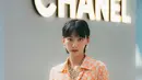 Angela Yuen menyalurkan gaya vintage dengan jumpsuit bermotif yang didominasi warna peach. Penampilannya dipermanis dengan perhiasan dan mini bag Chanel. [Dok/Chanel].