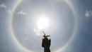 Fenomena halo matahari dengan latar depan monumen Malaikat Kemerdekaan di pusat kota Mexico City, Sabtu (7/7). Fenomena halo matahari terjadi karena pembiasan kristal es yang berada di sekitar Matahari yang membentuk semacam pelangi. (AP/Anthony Vazquez)