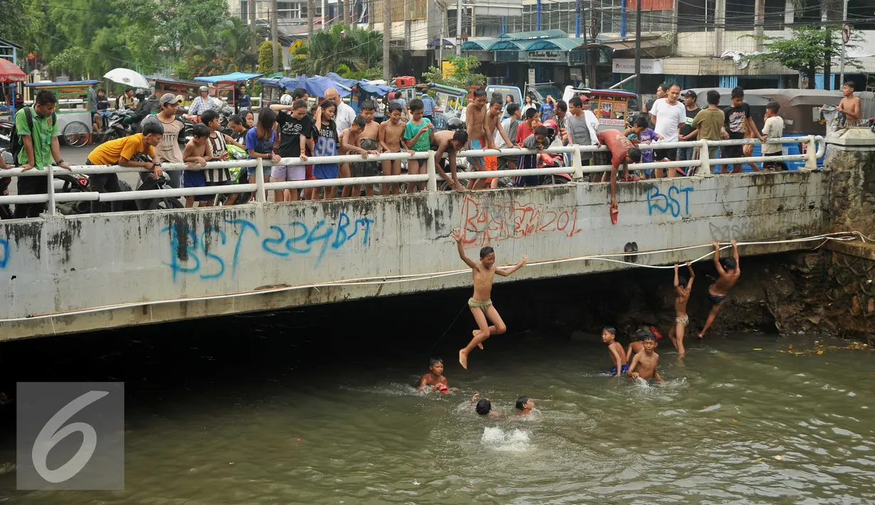 Aktivitas berenang di Anak Sungai Ciliwung di Jalan Labu, Kelurahan Mangga Besar menjadi tontonan warga, Jakarta, Selasa (17/5). Kondisi air yang mulai jernih dimanfaatkan mereka untuk bermain dan berenang. (Liputan6.com/Gempur M Surya)