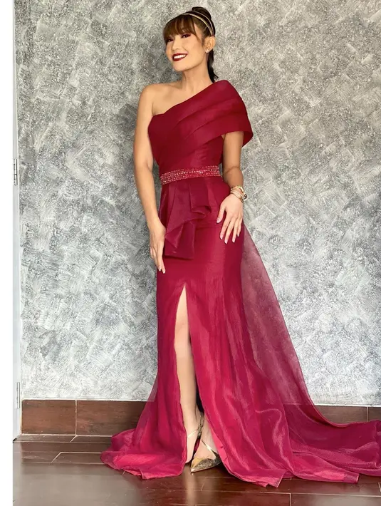 <p>Tampilan mewah lainnya dari Ayu Dewi dalam dress berwarna ungu tua. Kali ini Ayu Dewi memilih asymetrical dress bernuansa wine dengan belt berkilau di bagian pinggang, high slit, dan train yang cantik. Penampilannya ini disempurnakan dengan tatanan rambut yang dikepang tinggi dan diberi tambahan aksesori bando, serta makeup yang bold. Foto: Instagram.</p>