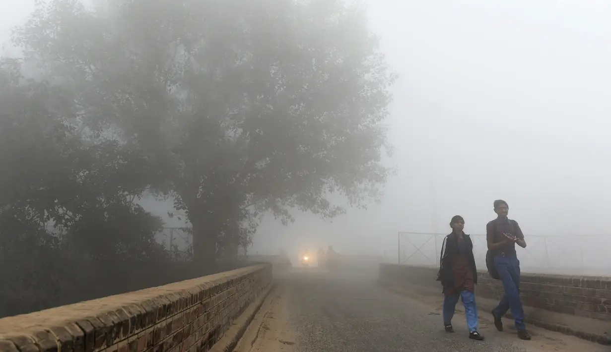 Pelajar India berjalan menuju sekolah saat kabut asap akibat polusi udara menyelimuti New Delhi, Rabu (8/11). Indian Medical Association menyarankan warga untuk tidak keluar rumah dan menghindari sedapat mungkin aktivitas fisik apapun. (PRAKASH SINGH/AFP)