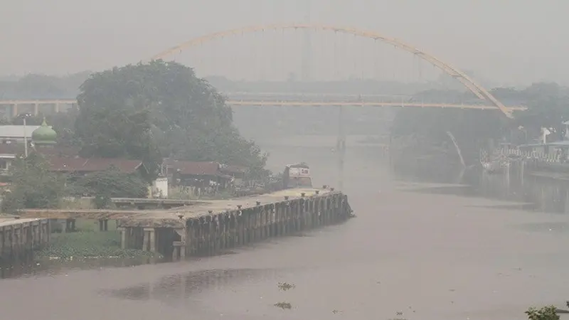 Kabut asap pekat menyelimuti rumah dan Jembatan Siak III di Pekanbaru mulai terlihat samar.
