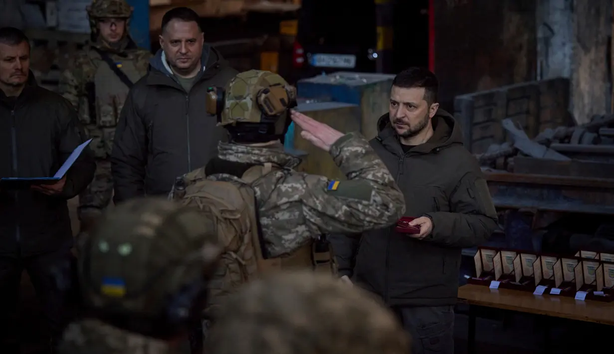 Presiden Ukraina Volodymyr Zelenskyy (kanan) memberikan penghargaan kepada seorang tentara di lokasi pertempuran terberat melawan Rusia di Bakhmut, Ukraina, 20 Desember 2022. Zelenskyy bertemu dan berbicara dengan tentara selama kunjungannya ke kota garis depan tersebut. (Ukrainian Presidential Press Office via AP)