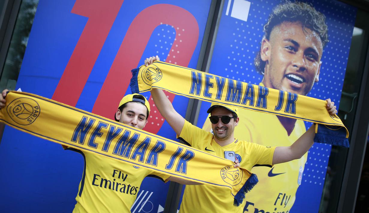 Fans berpose di depan gambar pemain baru Paris Saint Germain, Neymar Jr, di toko merchandise di Paris, Jumat (4/8/2017). Setelah resmi bergabung dengan Paris Saint Germain, jersey Neymar Jr langsung diburu suporter klub Ibu kota. (AFP/Benjamin Cremel)