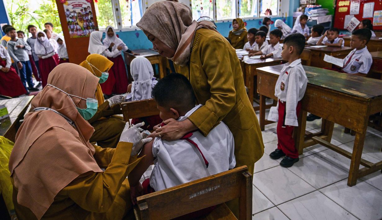 Salah satu siswa menerima vaksin difteri di sebuah sekolah dasar di Surabaya pada Selasa 4 November 2025. Pada tahap pertama yang digelar Agustus 2025 lalu, program ini difokuskan pada imunisasi Campak-Rubella (MR) untuk siswa kelas 1 serta Human Papillomavirus (HPV) bagi siswi kelas 5 dan 9. (Juni KRISWANTO/AFP)