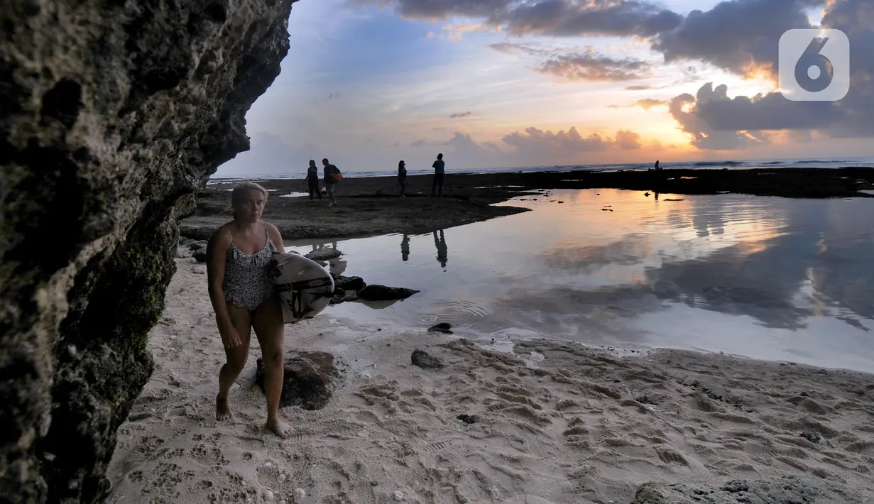 Wisatawan berjalan dekat kolam renang alami yang terbentuk saat air laut surut di kawasan Pantai Suluban, Uluwatu, Bali, Selasa (7/9/2021). Keunikan Pantai Suluban dengan kolam-kolam yang terbentuk di atas karang menjadi daya tarik wisatawan. (merdeka.com/Arie Basuki)