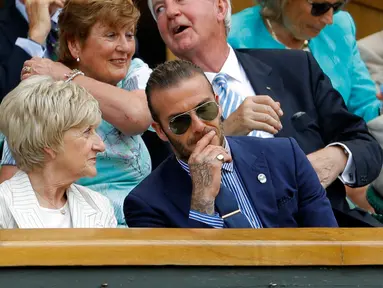 Aktor David Beckham berbincang dengan ibunya Sandra menyaksikan dari Royal Box pada hari kelima di Kejuaraan Tenis Wimbledon 2017 di London, Inggris (7/7). Beckham tampil dengan jas berwarna biru dan menggunakan kaca mata hitam. (AP Photo/Alastair Grant)