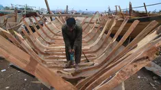 Tukang kayu Pakistan membuat kapal penangkap ikan di sebuah pelabuhan di Karachi (3/4). Pembuatan kapal buatan Pakistan menghasilkan ratusan kapal setiap tahun untuk memenuhi permintaan industri perikanan setempat. (AFP Photo/Asif Hassan)