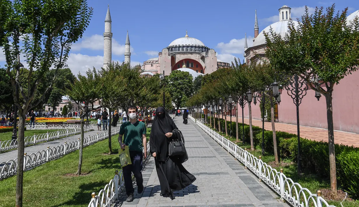 Orang-orang berjalan di depan Hagia Sophia di Istanbul, Turki pada 11 Juli 2020. Hagia Sophia, bangunan berusia 1.500 tahun, saat ini berubah statusnya menjadi masjid. (Ozan KOSE/AFP)