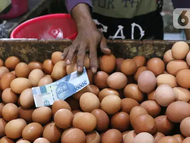 Pedagang telur ayam mengambil uang saat melayani pembeli di Pasar Kelapa Dua, Kabupaten Tangerang, Banten, Rabu (29/12/2021). Kementerian Perdagangan mencatat meroketnya harga telur ayam di sejumlah wilayah jelang pergantian tahun. (Liputan6.com/Angga Yuniar)