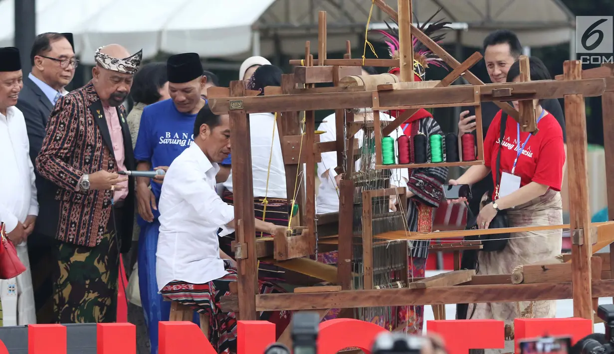 Presiden Joko Widodo mencoba alat penenun kain di Festival Sarung Indonesia 2019, Plaza Tenggara Kompleks GBK, Jakarta, Minggu (3/3). Festival ini untuk menghidupkan kesadaran generasi muda akan kekayaan budaya Indonesia. (Liputan6.com/Helmi Fithriansyah)
