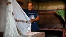 Seorang pekerja membilas kain saat proses pembuatan batik di sebuah bengkel di Banda Aceh, Aceh, Rabu (13/10/2021). Motif batik Aceh yang terkenal di antaranya adalah motif pintu Aceh, bunga jeumpa, tolak angin, rencong, gayo, dan pucok reubong. (Chaideer MAHYUDDIN/AFP)