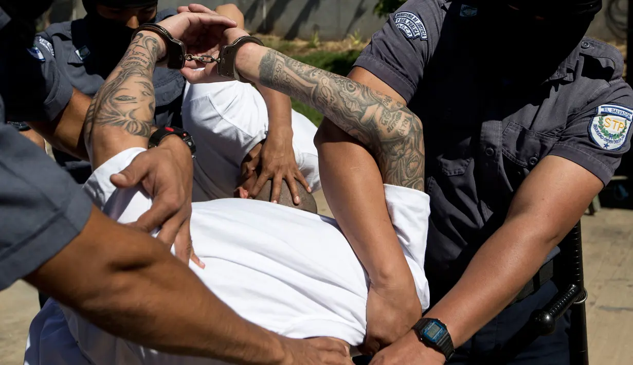 Petugas kepolisian menggelandang anggota geng Mara Salvatrucha di Zacatecoluca, El Salvador (31/1). Anggota geng tersebut dipindahkan ke penjara keamanan maksimum untuk menunggu persidangan. (AP Photo/Moises Castillo)