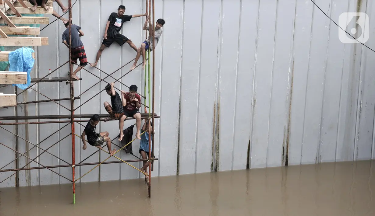 Warga bermain saat banjir merendam Underpass Senen, Jakarta, Selasa (25/2/2020). Hujan deras yang mengguyur Ibu Kota sejak dini hari tadi menyebabkan Underpass Senen terendam banjir setinggi dua meter sehingga mengakibatkan akses Cempaka Putih-Pasar Senen terputus. (merdeka.com/Iqbal Nugroho)