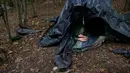 Seorang migran beristirahat di tenda yang dibuat dari lembaran plastik di kamp darurat di hutan di luar Velika Kladusa, Bosnia pada 25 September 2020. Bosnia menjadi salah satu tempat singgah para imigran dan pengungsi dalam perjalanannya ke Eropa Barat. (AP Photo/Kemal Softic)