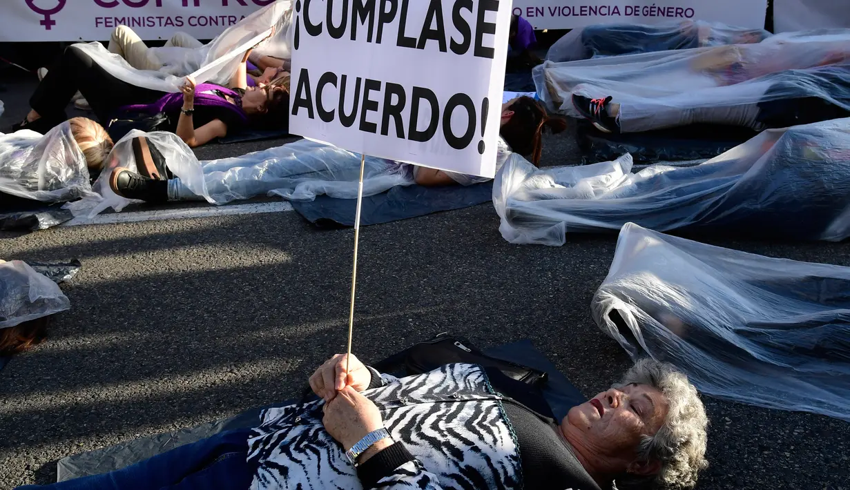 Seorang pengunjuk rasa berbaring di jalan dan memegang poster bertuliskan "Memenuhi kesepakatan!" saat melakukan aksi di Madrid, Spanyol (16/5). (AFP/Javier Soriano)