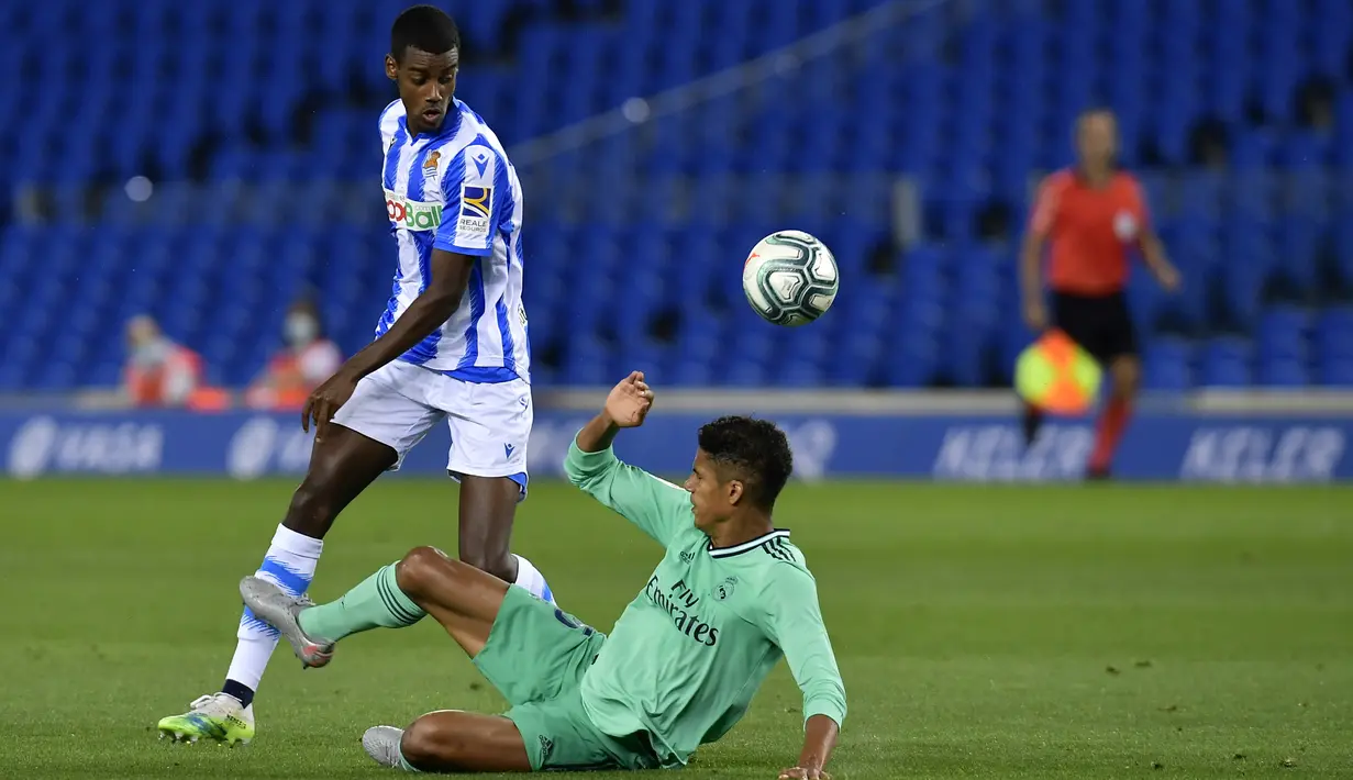 Pemain Real Madrid Raphael Varane (kanan) berebut bola dengan pemain Real Sociedad Alexander Isak pada pertandingan La Liga di Stadion Anoeta, San Sebastian, Spanyol, Minggu (21/6/2020). Real Madrid memuncaki klasemen sementara La Liga usai mengalahkan Real Sociedad 2-1. (AP Photo/Alvaro Barrientos)