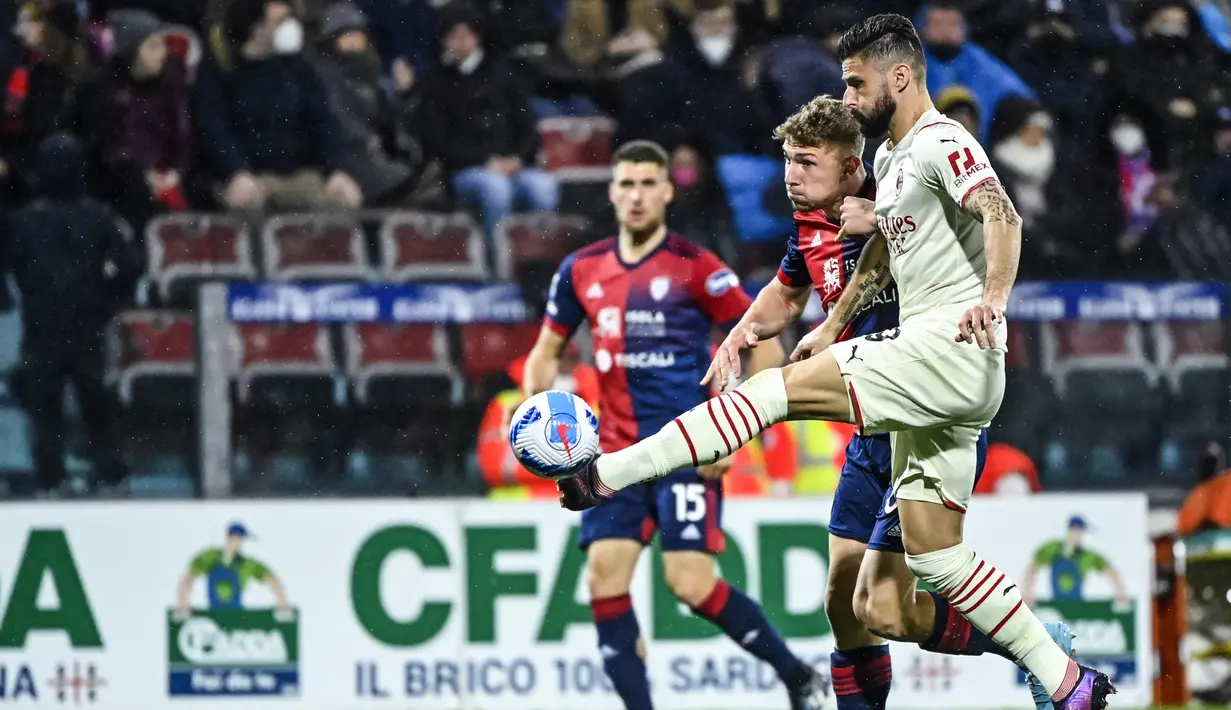 Penyerang AC Milan, Olivier Giroud (kanan) mengontrol bola dari kawalan bek Cagliari, Matteo Lovato selama pertandingan Liga Serie A Italia di Sardegna Arena di Cagliari, Italia, Minggu (20/3/2022). Dengan kemenangan ini, AC Milan kokoh di puncak klasemen dengan 66 poin. (AFP/Alberto Pizzoli)
