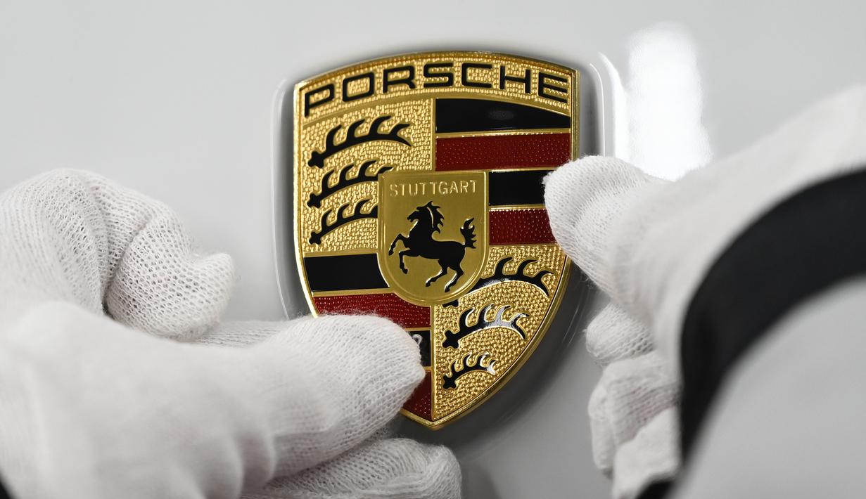 Mekanik memasang logo mobil listrik Porsche Taycan saat proses perakitan di pabrik perusahaan Porsche AG di Stuttgart, Jerman, Rabu (4/3/2020). Porsche Taycan merupakan mobil bertenaga listrik pertama  dari pembuat mobil mewah Jerman, Porsche AG. (AFP Photo/Thomas Kienzie)