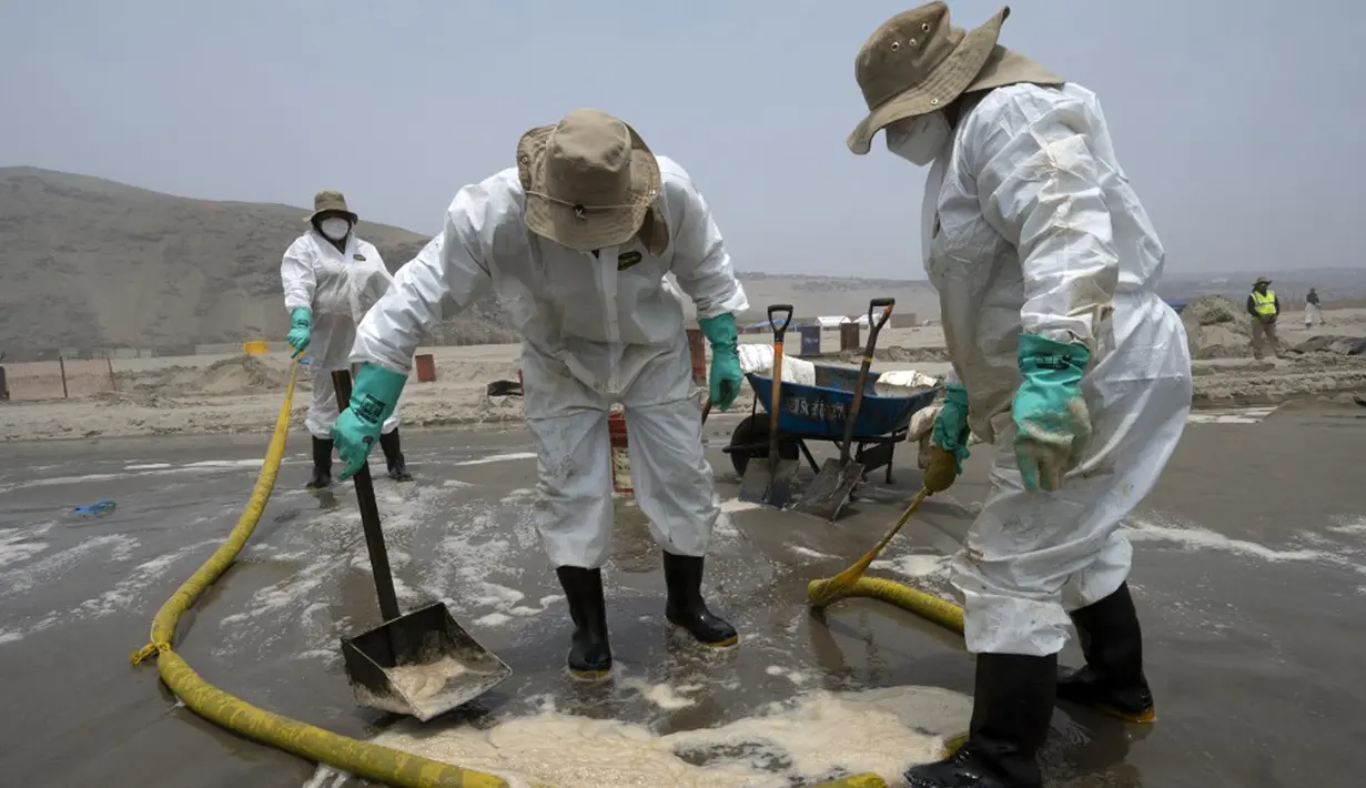 Petugas kebersihan bekerja untuk mengeluarkan minyak dari Pantai Cavero di Callao, Peru, 26 Januari 2022. Pembersihan Pantai Cavero dari tumpahan minyak kapal tanker Mare Doricum yang dihantam gelombang akibat letusan gunung berapi Tonga masih terus dilakukan. (Cris BOURONCLE/AFP)