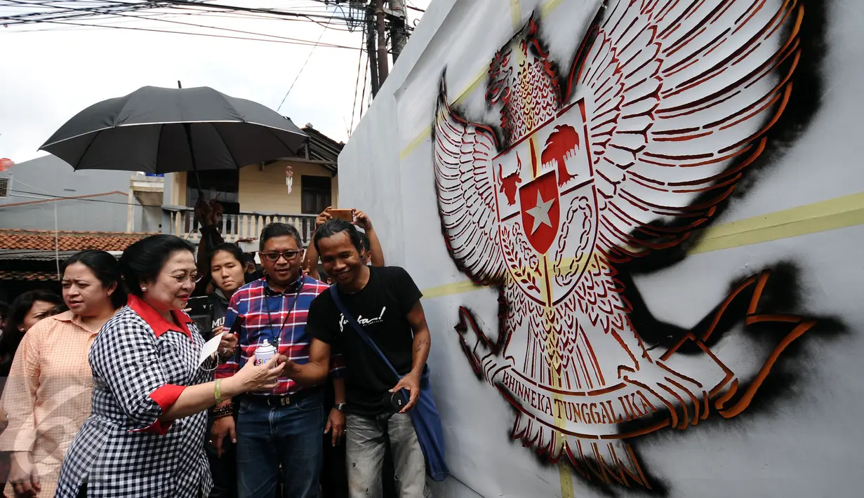 Presiden ke-5 RI Megawati Soekarnoputri saat akan mewarnai mural bergambar Garuda Pancasila di dinding TPS sebelum mengikuti proses pencoblosan Pilkada DKI 2017, di TPS 027 Kebagusan, Jakarta Selatan, Rabu (15/2). (Liputan6.com/Helmi Fithriansyah)