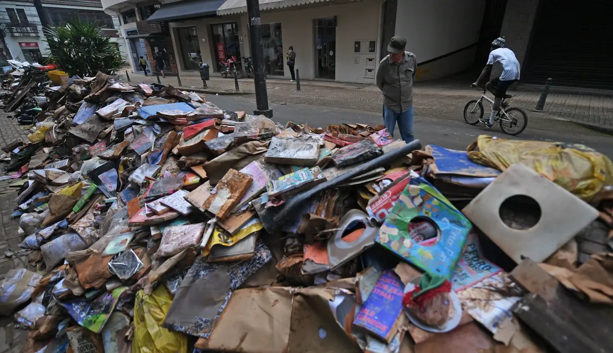 Ribuan buku rusak terlihat di jalan setelah hujan lebat membanjiri toko buku di Petropolis, Brasil, 19 Februari 2022. Sebanyak 136 jenazah telah diidentifikasi hingga kini, menurut pejabat pertahanan sipil, di kota wisata yang biasanya indah, sekitar 60 km utara Rio de Janeiro. (MAURO PIMENTEL/AFP)