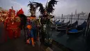 Sejumlah peserta mengenakan topeng dan kostum unik berdiri di St Mark Square selama Karnaval Venesia di Italia, Sabtu (27/1). Karnaval Venesia digelar 40 sebelum Paskah. (FILIPPO MONTEFORTE / AFP)