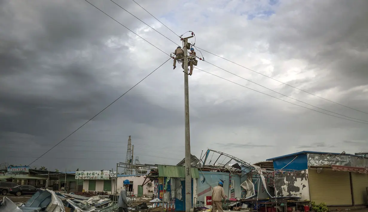 Beberapa pekerja memperbaiki jaringan listrik yang rusak akibat Topan Rammasun yang memporak-porandakan kota Zhanjiang di provinsi Guangdong, (20/7/2014). (REUTERS/Stringer)