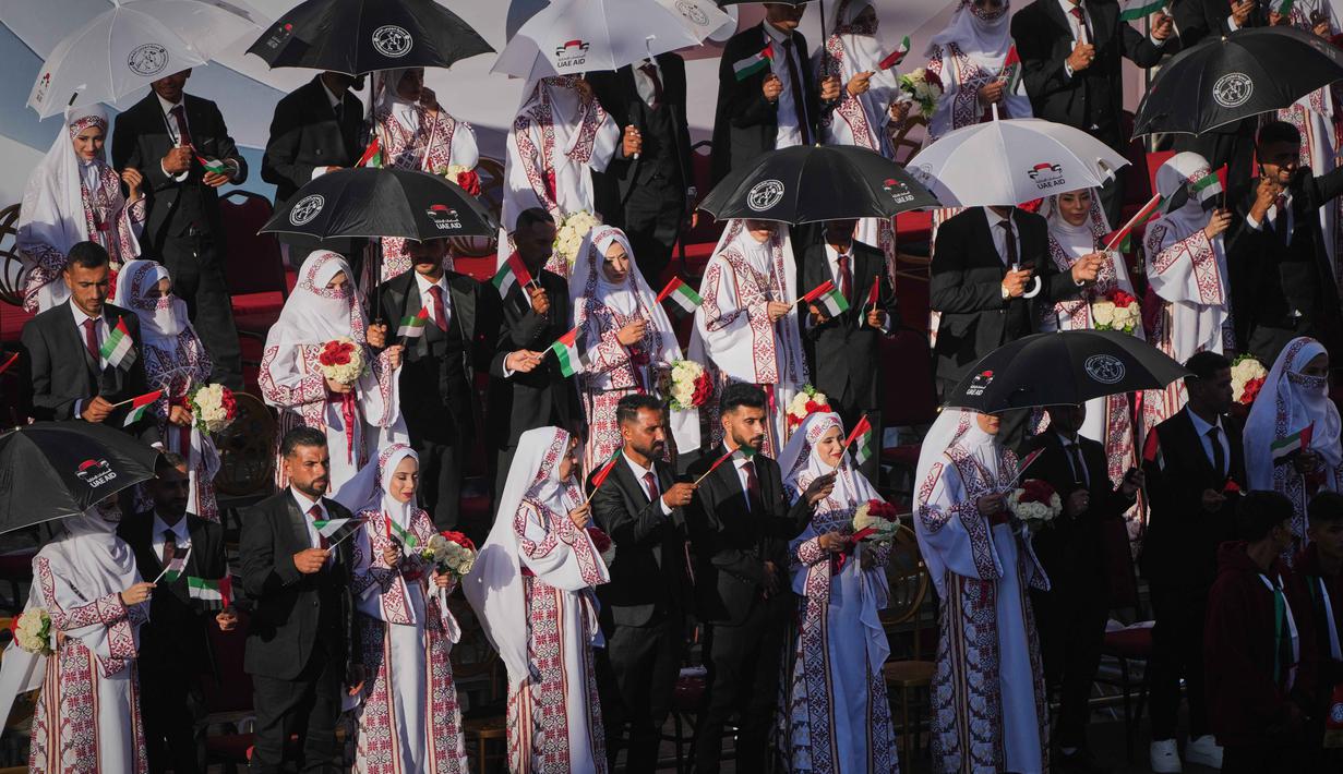 Prosesi akad nikah digelar di Khan Younis, di tengah puing-puing bangunan yang hancur akibat serangan Israel. Tampak dalam foto, pasangan Palestina berpartisipasi dalam upacara pernikahan massal di Kota Hamad, Khan Younis, Jalur Gaza, Selasa 2 Desember 2025. (AP Photo/Abdel Kareem Hana)