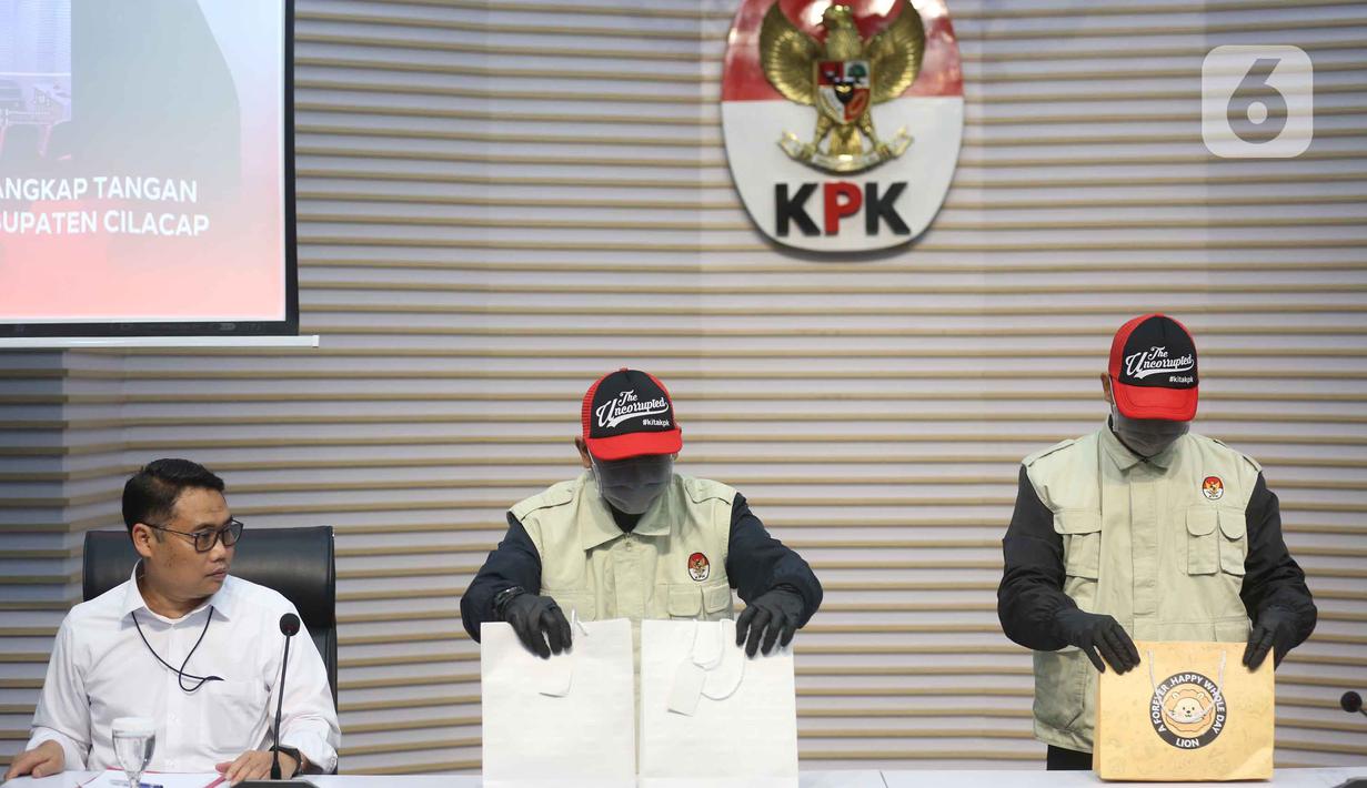 Bupati Cilacap Syamsul Auliya Rachman ditetapkan sebagai tersangka terkait dugaan pemerasan dan penerimaan lainnya di lingkungan Pemerintah Kabupaten Cilacap, Jawa Tengah. Tampak dalam foto, Deputi Bidang Penindakan dan Eksekusi Komisi Pemberantasan Korupsi (KPK), Asep Guntur Rahayu (kiri) menyaksikan petugas yang akan memperlihatkan barang bukti yang disita dari Operasi Tangkap Tangan (OTT) terhadap Bupati Cilacap, Jawa Tengah, Syamsul Auliya Rachman, di Gedung Merah Putih KPK, Jakarta, Sabtu (14/3/2026). (Liputan6.com/Helmi Fithriansyah)