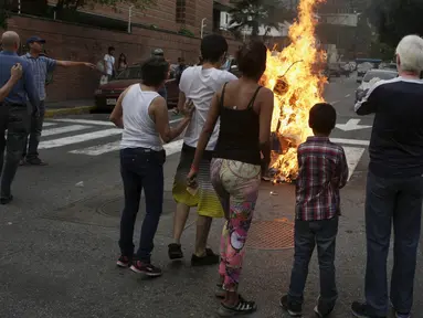 Patung yang dipasang gambar Presiden Venezuela Nicolas Maduro dibakar oleh warga di Caracas , Venezuela, (27/3). Hal ini dilakukan dalam perayaan Paskah di Caracas. (REUTERS / Marco Bello)