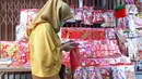 Seorang perempuan melewati kios pernak-pernik khas Imlek di kawasan Tangerang, Sabtu (6/2/2021). Pandemi virus corona COVID-19 membuat para pedagang pernak-pernik Tahun Baru Imlek di kawasan tersebut mengeluh karena menurunnya penjualan dibandingkan tahun-tahun sebelumnya (Liputan6.com/Angga Yuniar)