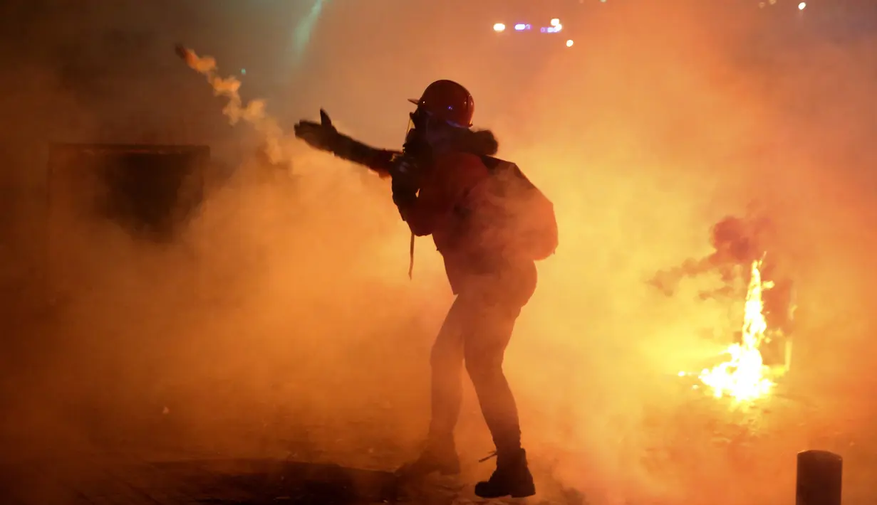 Demonstran antipemerintah melemparkan kembali tabung gas air mata kepada polisi antihuru-hara saat protes menentang elite penguasa di Beirut, Lebanon, Selasa (14/1/2020). Demonstran menganggap elite penguasa gagal mengatasi ekonomi yang menurun tajam. (AP Photo/Hussein Malla)